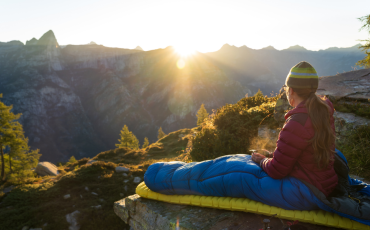 femme faisant du bivouac en motagne vue sur le lever du soleil a travers les montagnes 