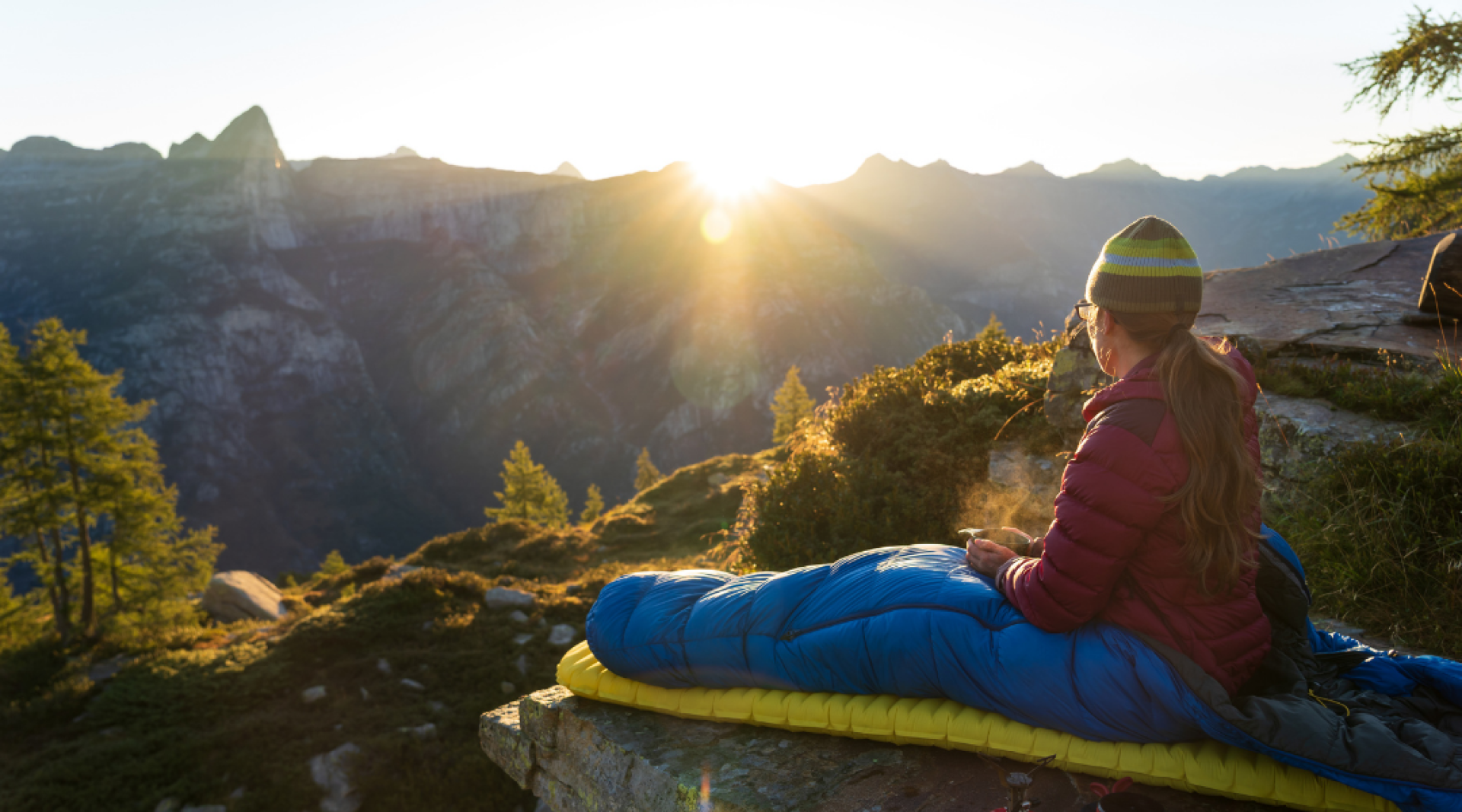 femme faisant du bivouac en motagne vue sur le lever du soleil a travers les montagnes 